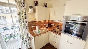 Een kleine keuken met een ingebouwde oven, een koffiezetapparaat en een spoelbak.
