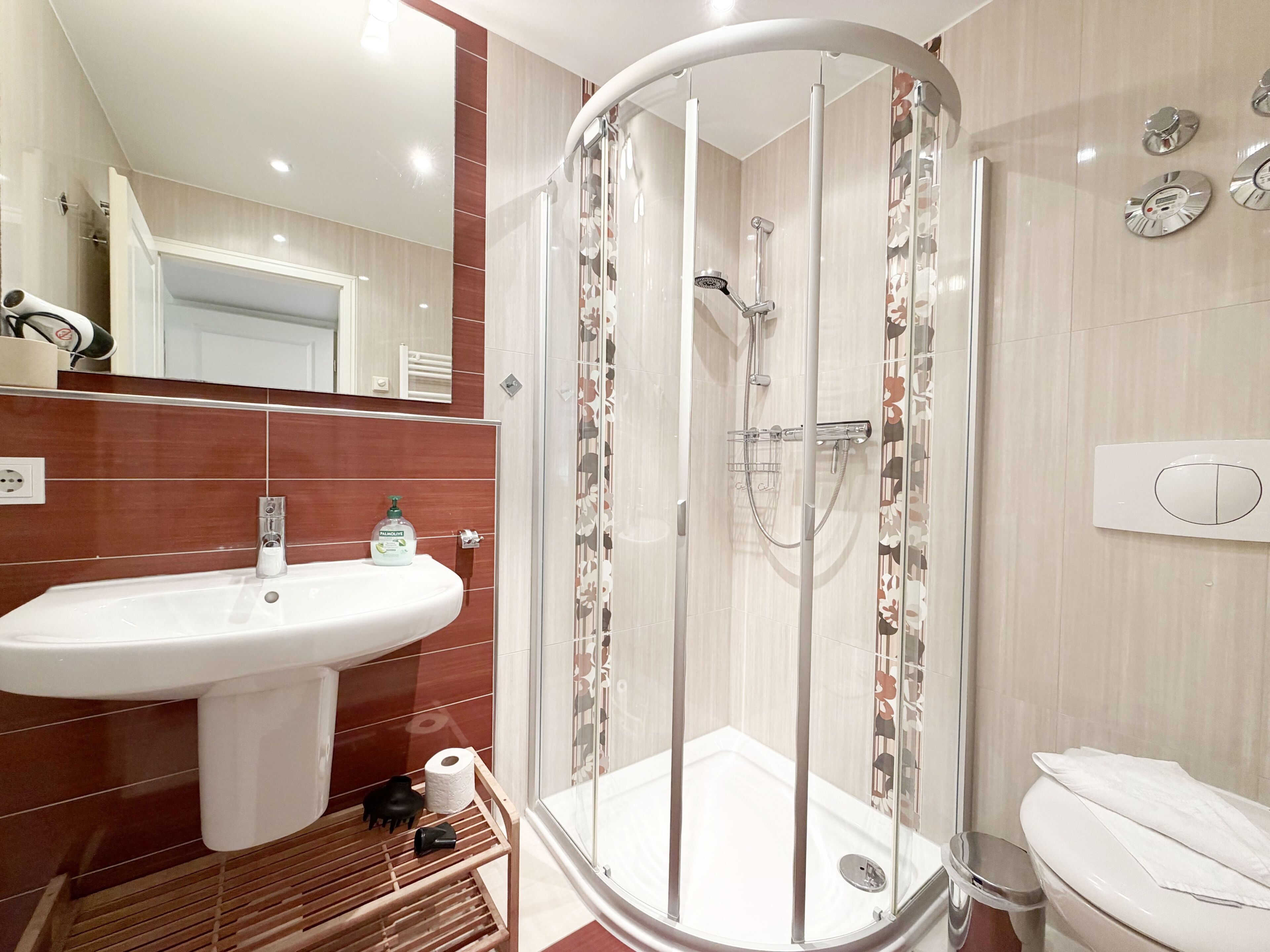 Un baño con ducha, lavabo, inodoro y espejo.