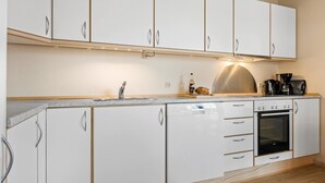 A kitchen with white cabinets, a dishwasher, an oven, and a coffee maker.
