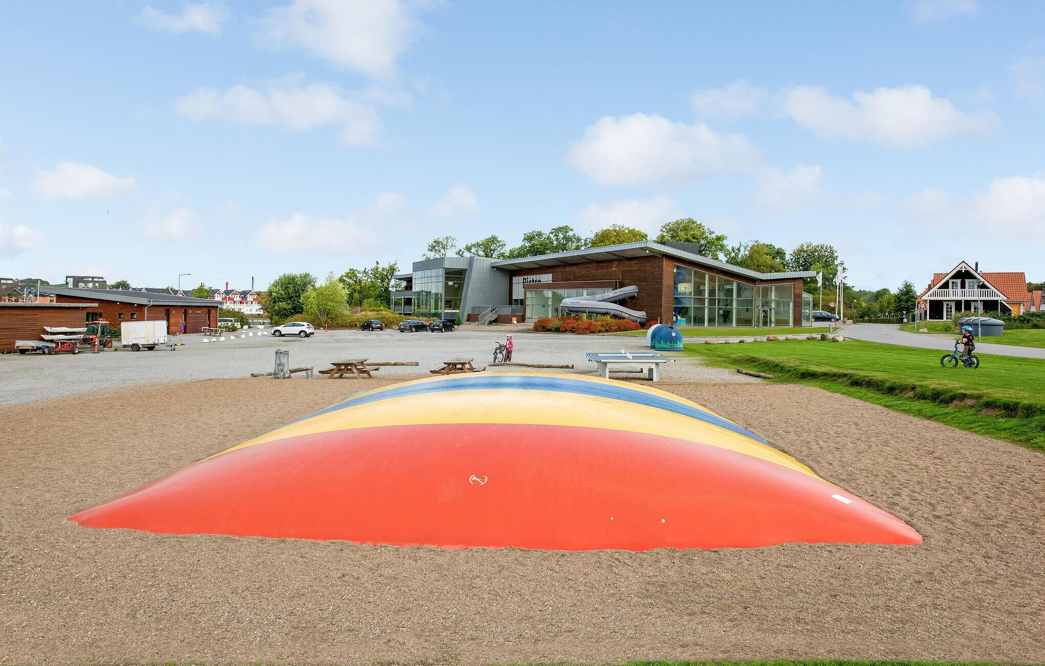 Een speeltuin met een kleurrijke glijbaan en een gebouw met een modern ontwerp op de achtergrond.