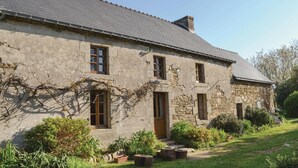 A stone house with a sloped roof, multiple windows, and a garden with potted plants and a pathway. - Beautiful home in Moelan sur Mer (Moelan sur Mer)