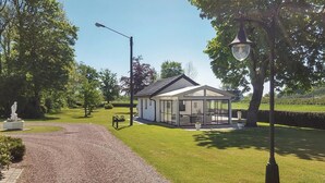 A modern house with a glass conservatory, surrounded by a well-maintained lawn and a gravel path. - Cozy home in Svedala with WiFi (Svedala)