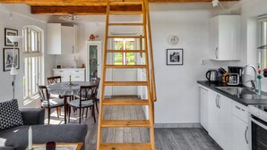 A modern kitchen with white cabinets, a wooden ladder, and a dining area with a table and chairs. - Cozy home in Svedala with WiFi (Svedala)