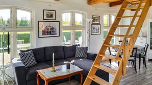 A cozy living room with a dark grey sofa, a small wooden table with a candle, and a wooden ladder. - Cozy home in Svedala with WiFi (Svedala)