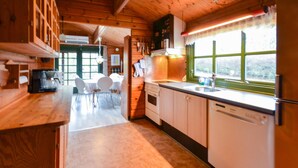 L'intérieur d'une cabane en bois comprend un coin cuisine, une table à manger et des chaises.