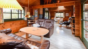 Un intérieur de chalet chaleureux avec des canapés en cuir, une table à manger en bois et un téléviseur.