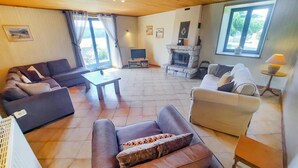 Un salón amplio con chimenea, sofás, una mesa de centro y un televisor.