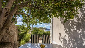 An outdoor seating area with a table and chairs, a bowl of fruit, and a view of the sea.