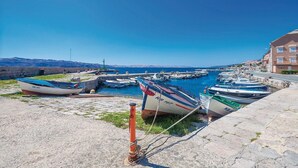 A harbor with boats docked, a stone wall, and buildings in the background.