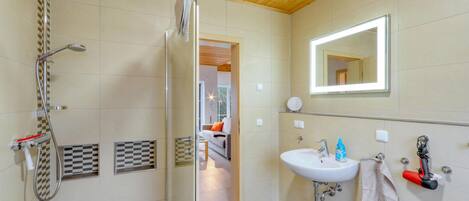 A modern bathroom with a glass shower enclosure, a white sink with a mirror, and a towel rack.