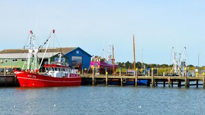 Ein rotes Fischerboot liegt an einem Steg, im Hintergrund ein blaues Gebäude.