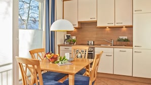 Una cocina moderna con armarios de madera, una mesa de comedor con sillas azules y una lámpara colgante.