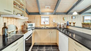 Una cucina con mobili in legno, un piano di lavoro nero, un forno a microonde, un lavello e una finestra vista casa.