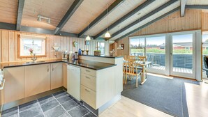 Una cucina moderna con mobili in legno, una grande isola e un'area pranzo con vista.