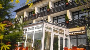Een gebouw met een glazen conservatorium, terras en potplanten.