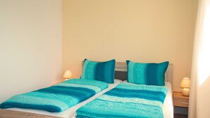 Un letto matrimoniale con una coperta a righe verde acqua e bianca, due cuscini abbinati e due lampade da comodino su un comodino.