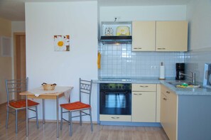 Une cuisine compacte équipée d’une cuisinière, d’un four et d’un petit coin repas avec deux chaises et une table.