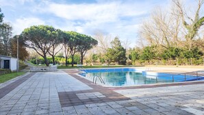 Une piscine dotée d’une terrasse carrelée, entourée d’arbres et d’une pelouse.