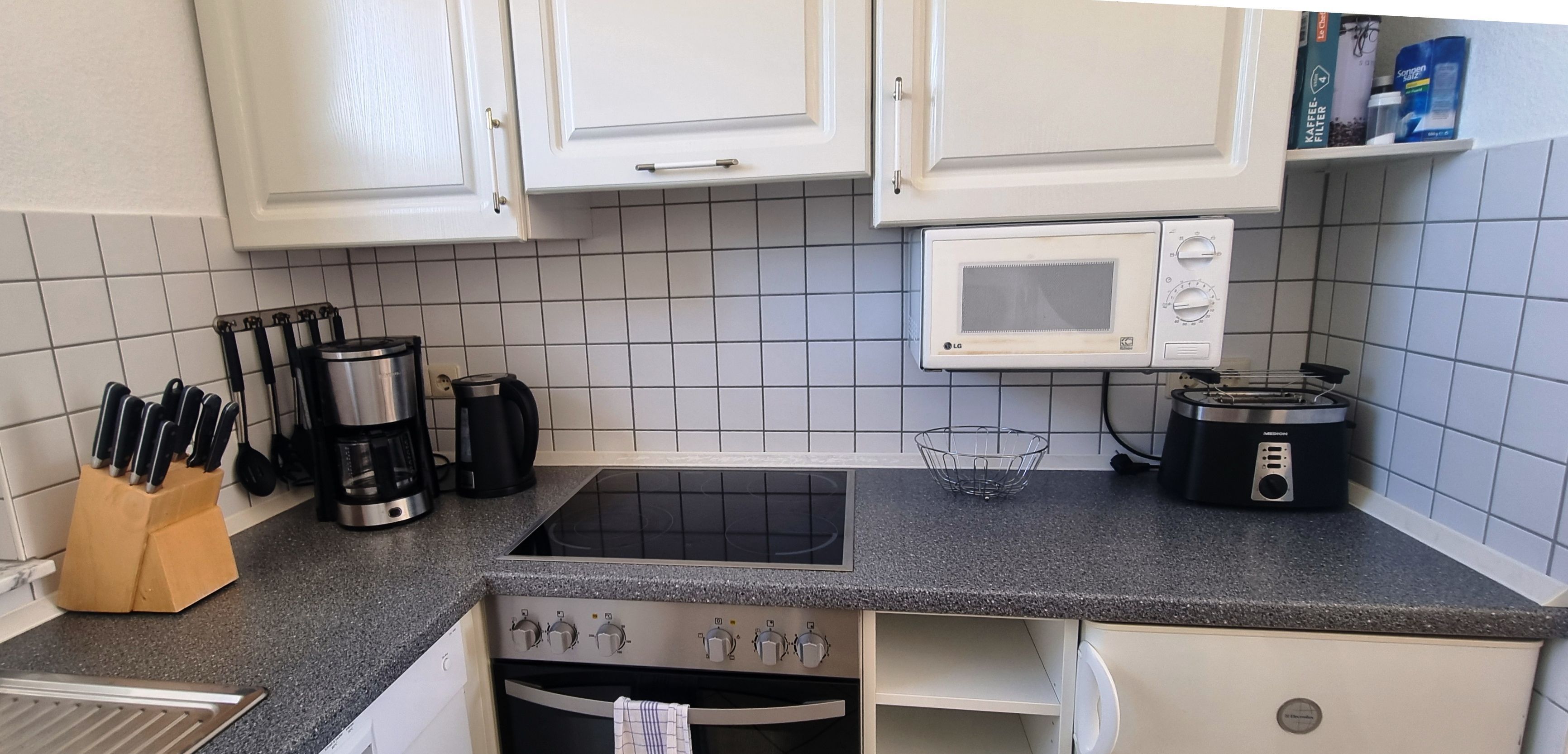 A kitchen with white cabinets, a microwave, a coffee maker, and a toaster.