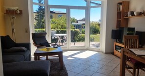 Un salon avec un canapé, un fauteuil, une table, un téléviseur et une bibliothèque.
