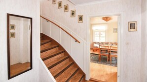 A staircase with wooden steps and a handrail, leading to a dining area with a table and chairs. - Beautiful home in Dalum with kitchen (Dalum)