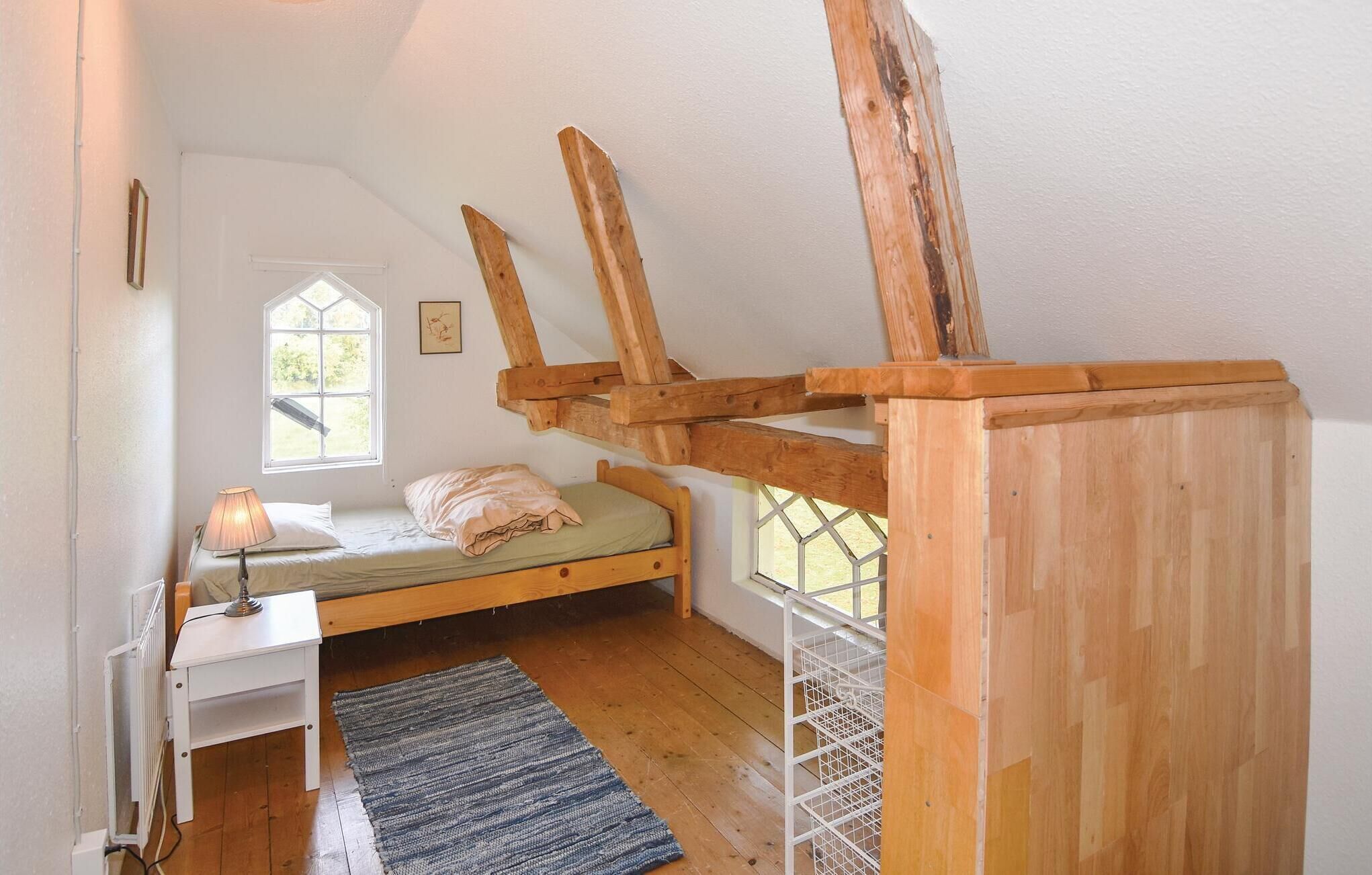 Une petite chambre mansardée, chaleureuse et accueillante, avec un lit simple, un bureau et une fenêtre.