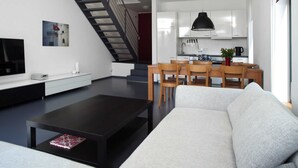 Una sala de estar moderna con un sofá, una mesa de centro y una escalera que lleva a una cocina.