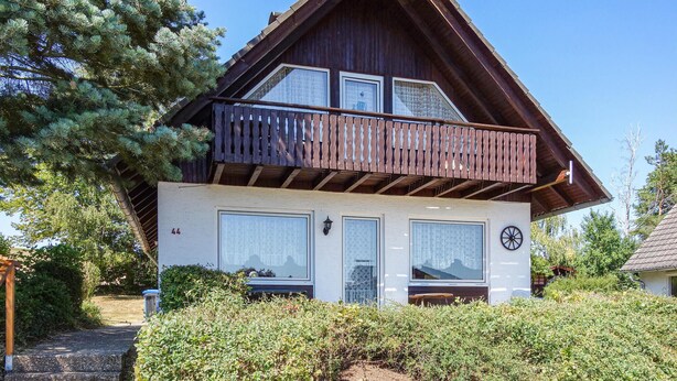 A two-story house with a balcony, large windows, and a door with a number '44' on the wall.