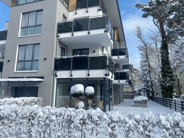 A multi-story building with balconies, large windows, and snow-covered surroundings.