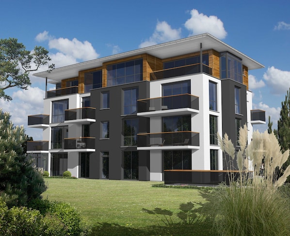 Un immeuble moderne à plusieurs étages, doté de balcons, de grandes fenêtres et d’une pelouse bien entretenue.