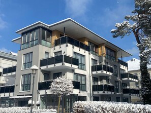 Un immeuble moderne à plusieurs étages, doté de balcons, de grandes fenêtres et d’un toit plat.
