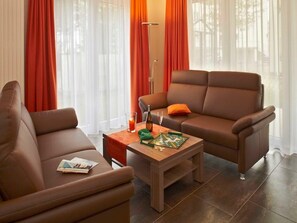 Un salon moderne avec deux canapés marron, une table basse en bois et un lampadaire.