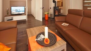 Ein modernes Wohnzimmer mit einer Couch, einem Couchtisch mit einer Kerze und einem Fernseher.