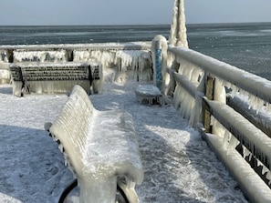 Un banc et une rambarde recouverts de glace, avec vue sur l’océan.