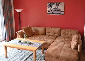 Un salon avec un canapé d’angle marron, une table basse en bois et un lampadaire.