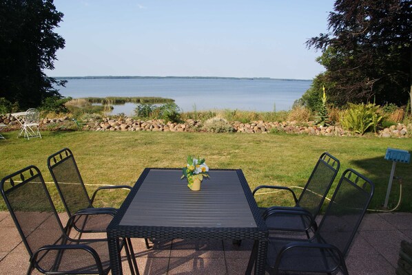 Une terrasse avec une table et des chaises donnant sur un lac.