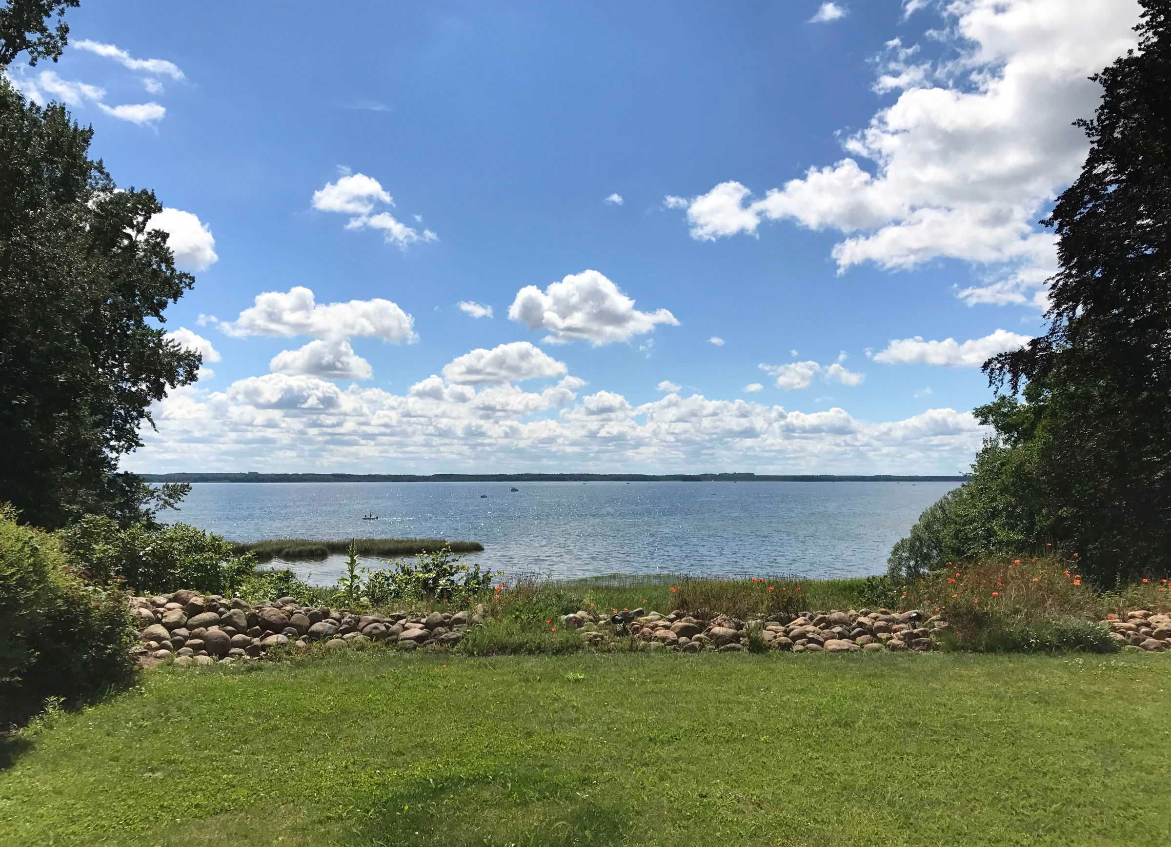 A grassy area with a view of a lake and distant shoreline.