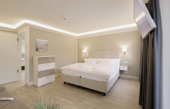 A modern hotel room with a large bed, bedside tables, a wardrobe, and a flat-screen TV. - Nice apartment in Binz with indoor swimming pool (Prora/Rügen)
