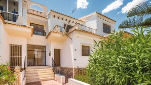A two-story building with a balcony on the upper floor, a staircase leading to the entrance, and a well-maintained garden in the foreground. - 2 bedroom stunning apartment in Rojales (Rojales)