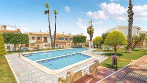 A swimming pool with a tiled deck, surrounded by palm trees and a well-maintained lawn. - 2 bedroom stunning apartment in Rojales (Rojales)
