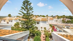 A view of a residential area with white buildings, a prominent pine tree, and a clear blue sky. - 2 bedroom stunning apartment in Rojales (Rojales)