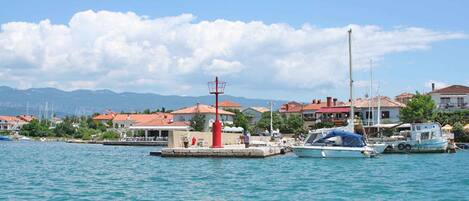 A marina with boats docked, a red lighthouse, and buildings with red roofs.
