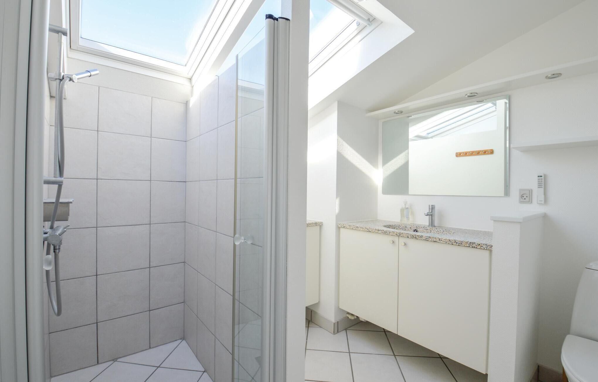 Ein modernes Badezimmer mit Oberlicht, Dusche und Waschtisch mit Spiegel.