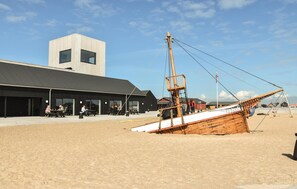 Un edificio frente a la playa con un ventanal grande y una ventana más pequeña a un lado.