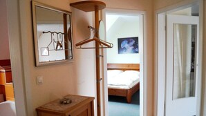 A bedroom with a wooden bed, a bedside table, a mirror, and a wooden hanger stand. - Große Kastanie 57 - between the Baltic Sea and the city center - Ferienwohnung große Kastanie (Graal-Müritz)