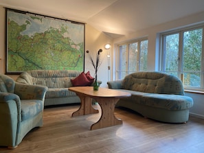 A living room with a large map, two sofas, a wooden coffee table, and a window with a view. - 2) Holiday apartment 3-room, upper floor, 90m² - Landhaus Alte Schule near (Alt Bukow)