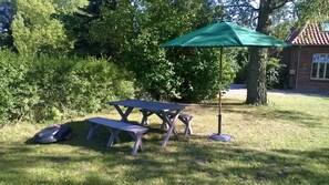 A picnic table with benches and a green umbrella in a grassy area with trees and a building in the background. - 2) Holiday apartment 3-room, upper floor, 90m² - Landhaus Alte Schule near (Alt Bukow)
