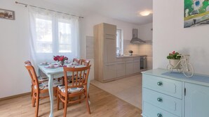 Una cocina compacta con zona de comedor, sillas de madera, un mueble azul claro y un cuadro en la pared.