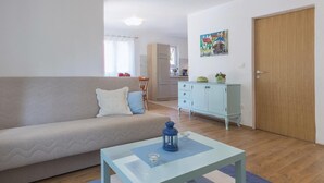 Una sala de estar con un sofá, una mesa con un farol, un armario y una puerta.