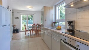 Una cocina moderna con zona de comedor, ventanas amplias y cafetera.